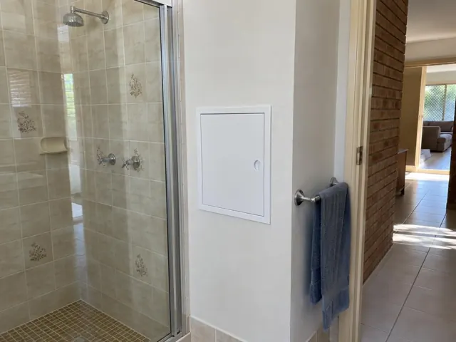 Bathroom shower wall with a small white access panel and tiled shower in Wetherill Park